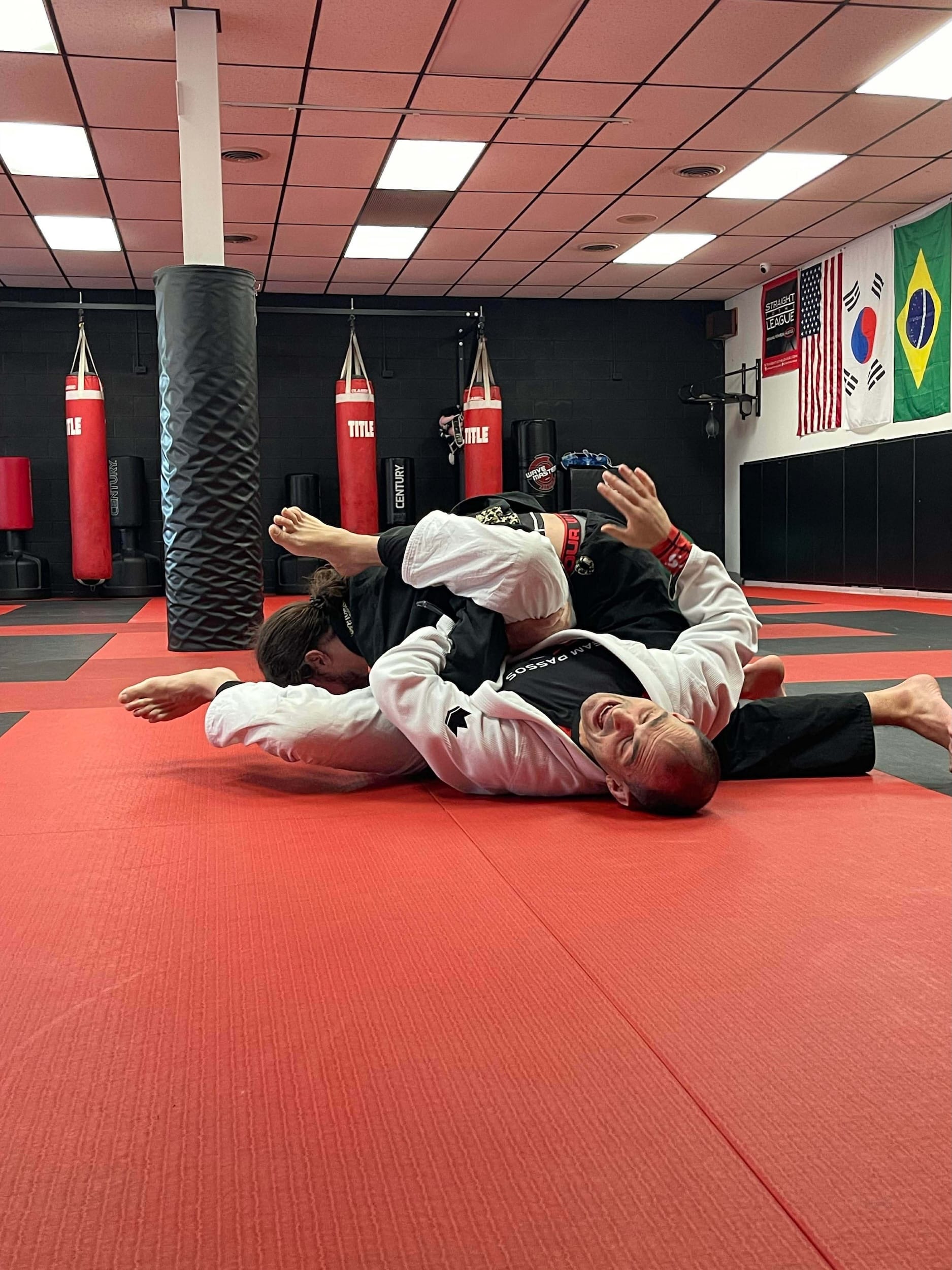 West Karate & Brazilian Jiu Jitsu students grappling on mats wearing gi uniforms.